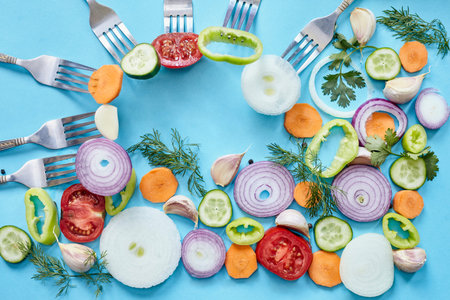 Onion rings on blue background. Fresh organic onion, garlic and bell pepper, celery, dill vegetables with copy space. Vegetarian backgroundの写真素材