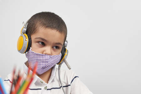 Young kid in headphones doing online exercises via laptop. Learning foreign language online or distance education, e-learning conceptsの写真素材