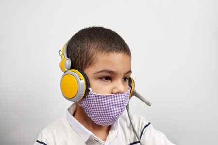 Young kid in headphones doing online exercises via laptop. Learning foreign language online or...