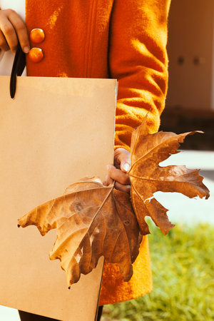 Big autumn sale. Woman holding a big fall leaf and shopping bag. Big Fall season sale discount