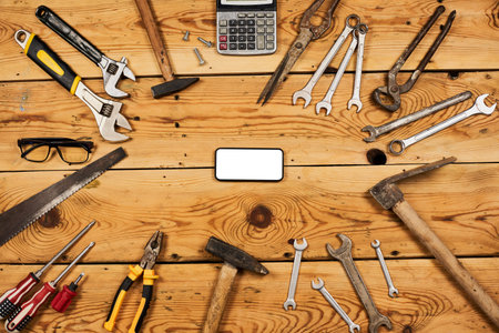 Different handy tools placed around the mobile phone with blank screen