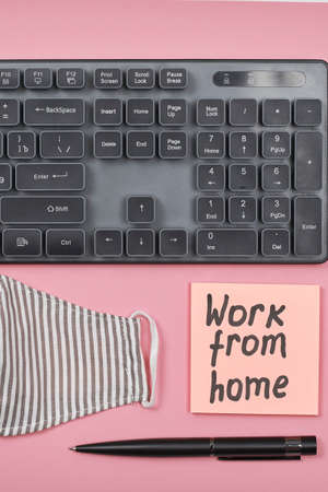 Computer keyboard, eyeglasses, face mask and sticky notes on the pink background with Work from home textの写真素材