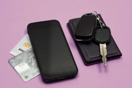 Car keys, mobile phone and credit cards on blue background. Top view. Do not forget to take car keys, money and smartphone before leaving homeの写真素材