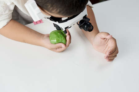 A boy in head magnifying glasses headset learning Incredible chemistry of slimes. Tactile play or sensory play for older kidsの写真素材