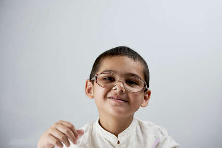 Portrait of cheerful 7 years old mixed race boy against the white background. A smart schoolboy portraitの写真素材