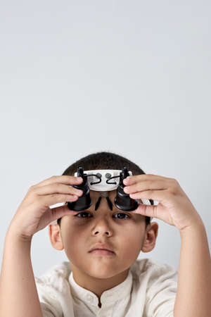 Vertical shot of a boy in headband magnifying glass looking at cameraの写真素材