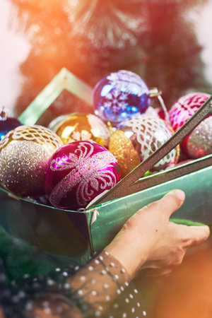 Close-up view of woman hands holding a box of Christmas tree decorations and ball ornamentの写真素材