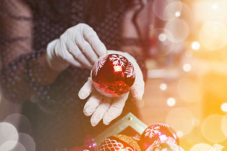 Female holding christmas toy. A woman in medical gloves preparing Christmas decorations. Covid-19 and Xmas conceptの写真素材