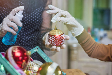 A boy helping his mom to disinfect Christmas ornate. Mother and son in medical gloves cleaning...