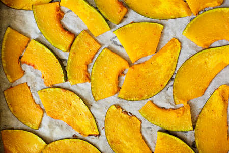 Overhead view of tasty baked pumpkin slices. A pan with baked, seasoned pumpkin slices on parchment paperの写真素材