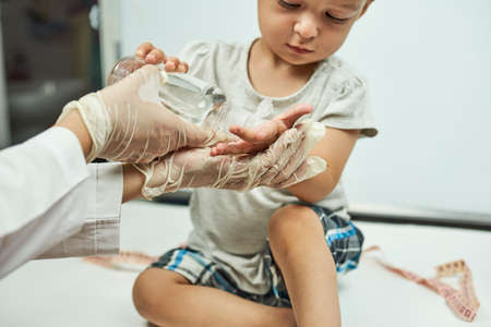 Doctor putting hand sanitizer to baby hands. Teaching a baby boy hand washing and hygiene. Physical examination of the 1-year-old baby boy. Well-baby examの写真素材
