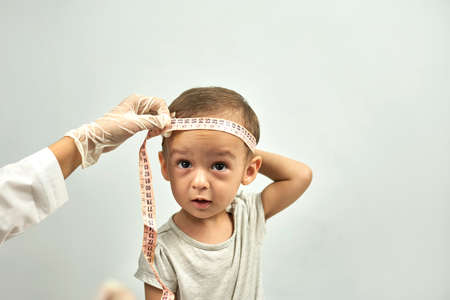 Doctor measuring baby head circumference. Pediatrician place measuring tape around your baby head and record its size. Well-baby exam. Regularly scheduled medical check-upの写真素材