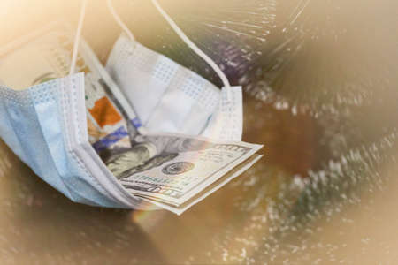 US dollars hanged with face mask on the Christmas tree as a gift. Celebrating winter and Christmas holidays in the new normal with coronavirus infectionの写真素材