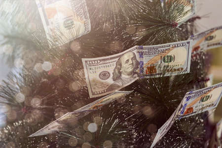 Financial Christmas tree. Festive Xmas tree decorated with hundred US dollars instead of Christmas ornamentsの写真素材