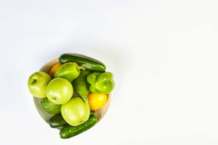 A bowl full of raw organic vegetables and fruits on white background with copy spaceの写真素材