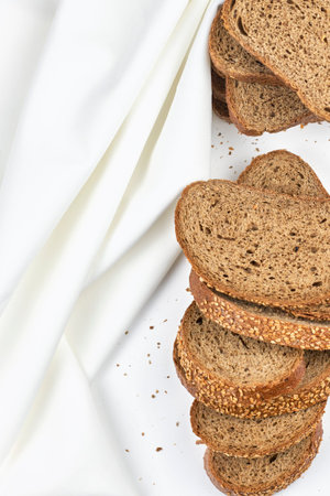 Pile of loaf bread slices on white fabric textile with copy space