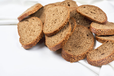 Pile of loaf bread slices on white fabric textile with copy space