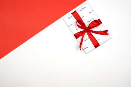 X-mas gift wrapped in paper with Christmas prints and tied with black ribbon. Christmas present box on white backgroundの写真素材