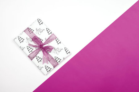 X-mas gift wrapped in paper with Christmas prints and tied with black ribbon. Christmas present box...
