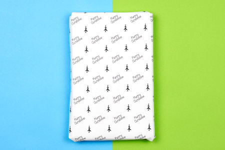 Xmas present wrapped in paper with festive prints. Christmas gift on white background. Homemade...