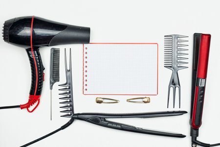 Working table of hairdresser with accessories and notepad on white. Females hairstylist workspace with hair cutting tools - combs, hair iron, hairdryer and notepadの写真素材