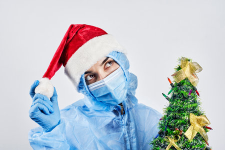 A nurse holds Christmas ornaments. A coronavirus hospital worker in protective workwear. Celebrating Christmas in hospital. Doctor celebrate New Year at workの写真素材