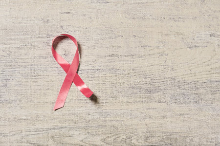 A pink cancer awarness ribbon on wooden desk