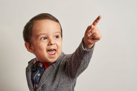 Funny portrait of a 2-years-old boy in a handmade elegant suit. A kid boy making a funny foolish face. Mixed-race baby boyの写真素材