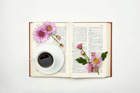 Reading a book in spring. A book with fresh spring flowers and a cup of coffee. Cozy morning with refreshing black coffee and an interesting bookの写真素材