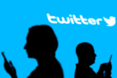 Tashkent, Uzbekistan - March 4, 2021: Silhouette of people over popular microblogging and social networking service - Twitter logologotype on a large screenのeditorial素材