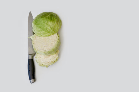 Sliced fresh cabbage and kitchen knife on white background. Top view of organic cabbage cuts on kitchen tableの写真素材