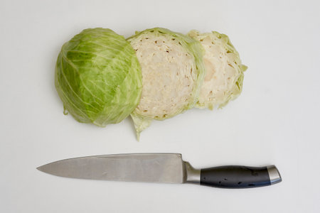 Sliced fresh cabbage and kitchen knife on white background. Top view of organic cabbage cuts on kitchen tableの写真素材