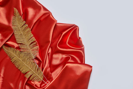 Decorative golden leaves on red textile backdrop. Bright, glamour autumnal concept with fake fall...