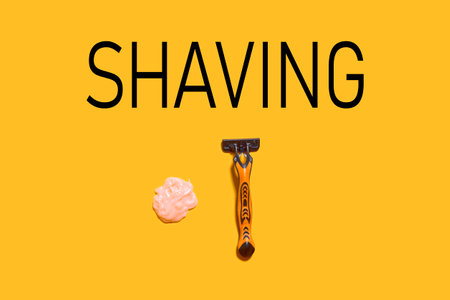 Shaving foam gel and razor on orange background. A multiple use shaving razor and cream. View from aboveの写真素材