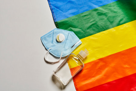 LGBT rainbow flag and  personal hygiene items - face mask n95 respirator and bottle of disinfectantの写真素材