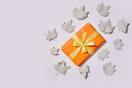 Gift boxes and fall leaves on white background. Creative lay out of autumn leaves and orange present boxes from above. Top viewの写真素材