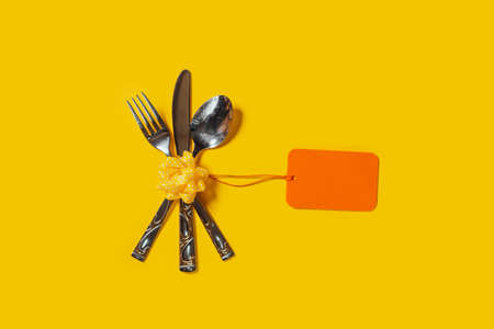 Vintage silverware with an empty tag on bright yellow backgroundの写真素材