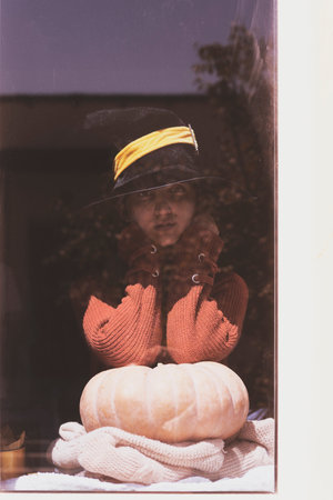 Halloween lady wearing witch cup. A woman in witch hat and Halloween pumpkin near the windows....
