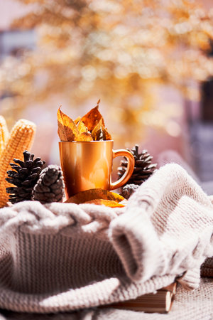 Corns, autumn leaves, pine cones and coffee cup on windowsill. Creative autumnal background near the...