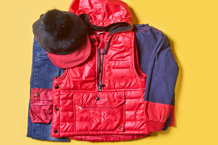 Baby autumn wear clothes on yellow background. Top view. Overhead view of warm kid autumn clothes on colored backdropの写真素材