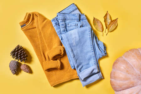 Baby autumn wear clothes on yellow background. Top view. Overhead view of warm kid autumn clothes on colored backdropの写真素材