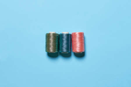 Sewing items flat lays from above. Collection of threads for sewing on bright blue backgroundの写真素材