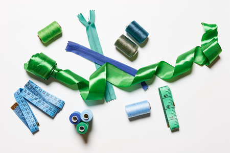 Sewing items from above. Flat lay composition with sewing accessories on light color background. Items for sewing, Sewing clothes, measuring tape, tailoring scissors, threads, buttons and needlesの写真素材