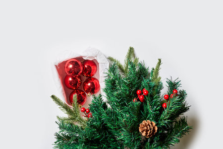 Branches of spruce tree with pine cones and Christmas toy decorations on white background. Top view....