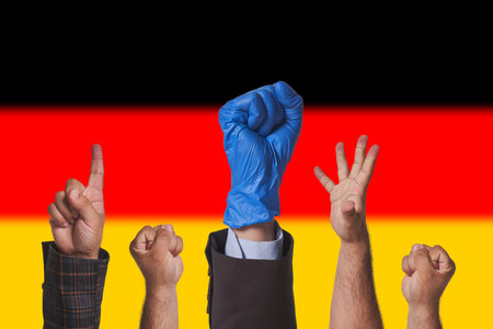 Protests in Germany. Workers, trade unions protesting against new rules, new laws in Germany. Hand of protesters against German national flagの写真素材