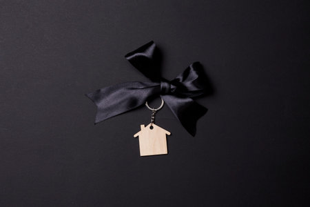 Black Friday concept. Buy a house with discount. A miniature house model with black ribbon