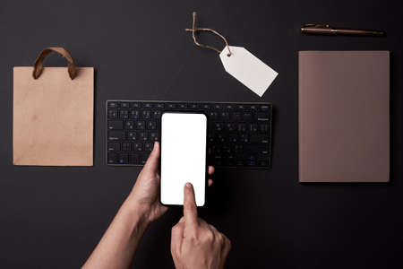 Black Friday concept. Shopping online. A person ordering gifts, clothes and other items in online shop. Shopping bag, gift box, computer keyboard from aboveの写真素材