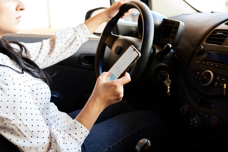 Young multiracial woman texting and driving car. Woman using cellphone while driving car. Female...