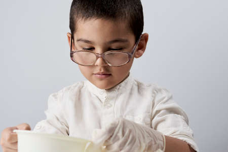 Little boy scientist in white making experiments against the white backgroundの写真素材