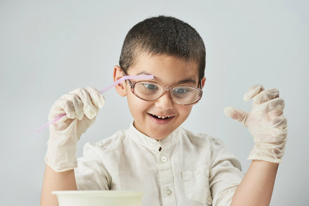 Funny kid making experiments at the workshop and exploring the world of chemistry against the white backgroundの写真素材